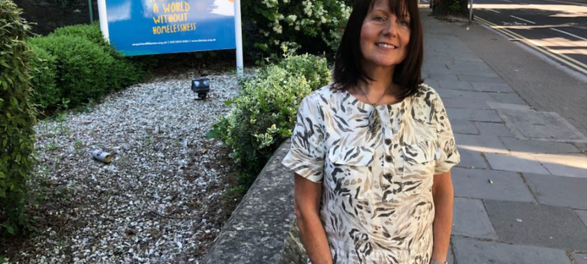 Frances stands outside the Llamau offices smiling for the camera