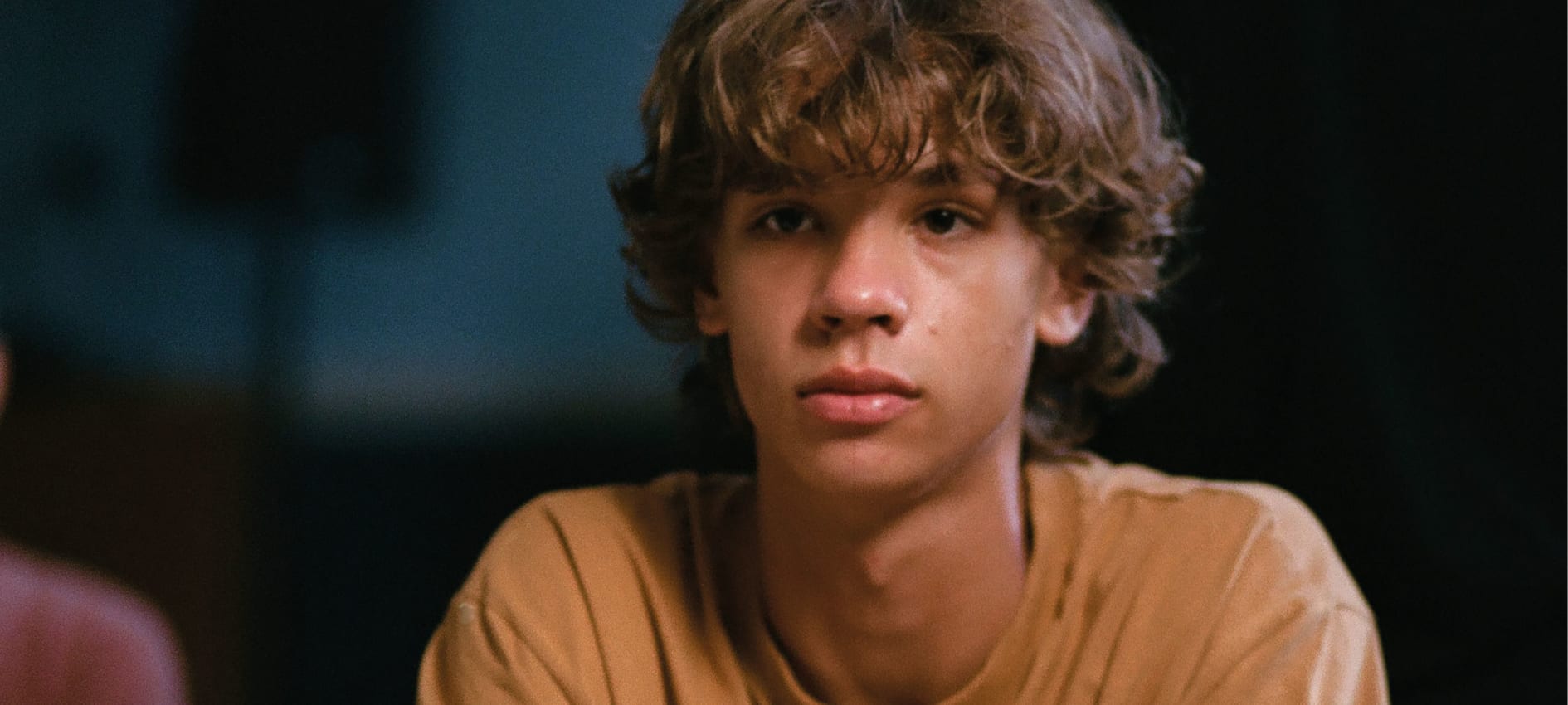 A young boy stares solemnly at something off camera